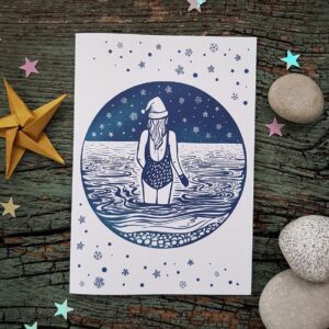 Isle of Portland themed Christmas featuring a wild, sea swimmer swimming off Chesil Beach in the snow and wearing a Christmas hat.