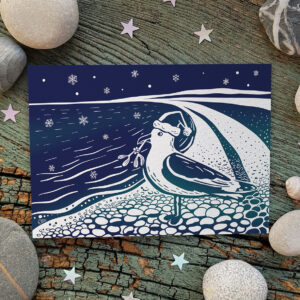 A quirky, fun coastal Christmas card featuring a festive seagull (complete with Christmas hat and mistletoe) on Chesil beach looking out to sea.